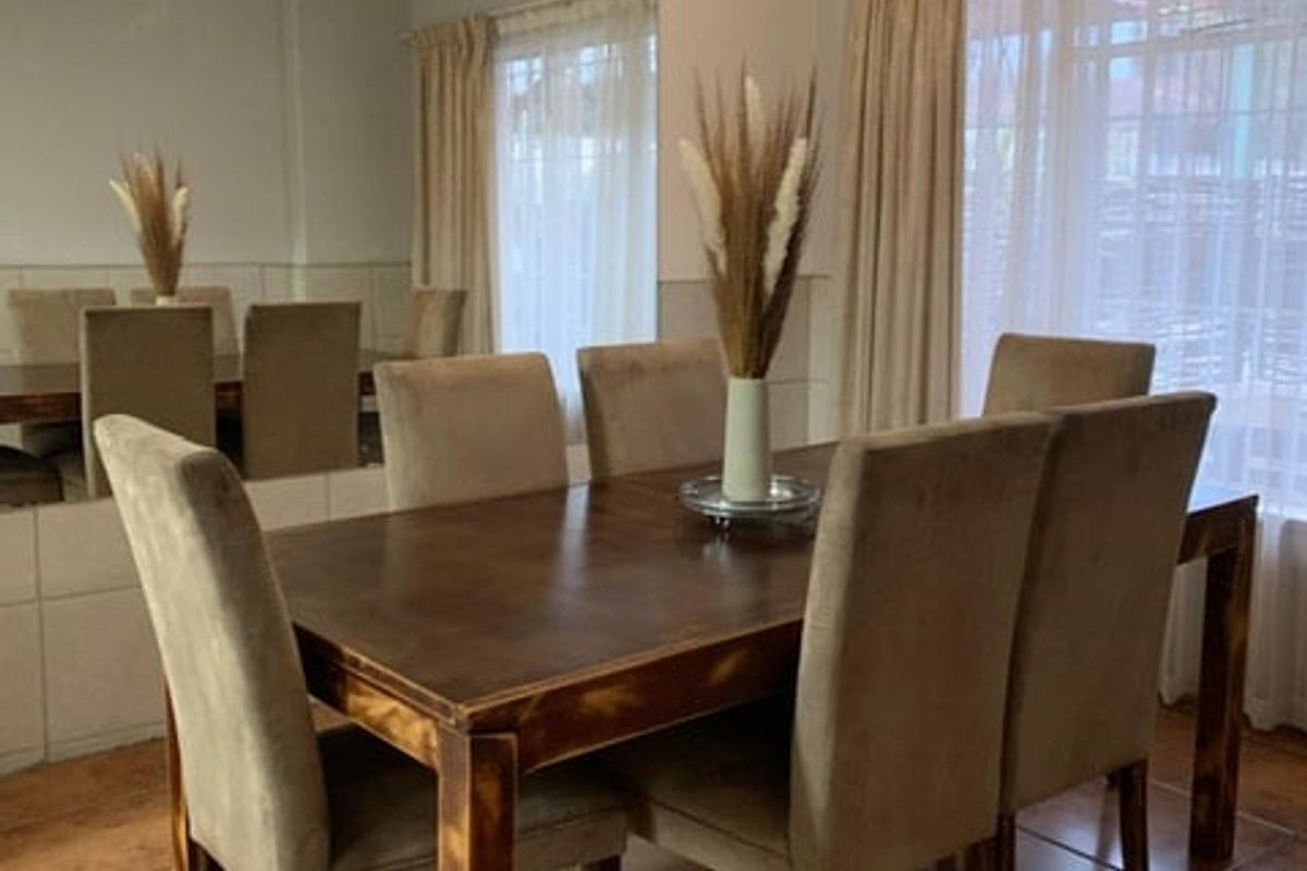 A dining room featuring tiled flooring and a large wall-mounted mirror, providing a functional space for family meals.