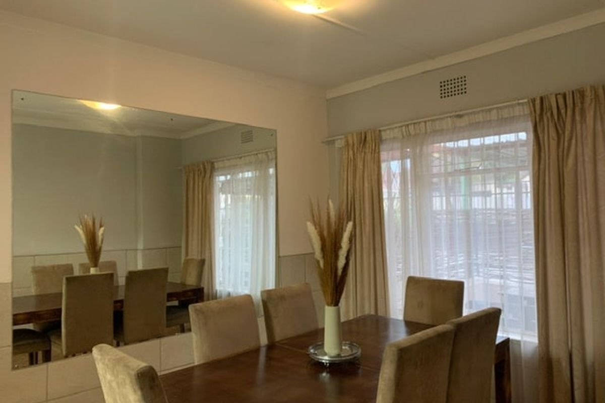 A dining room featuring a large wall-mounted mirror, neutral wall finishes, and window treatments, providing a functional space for meals.