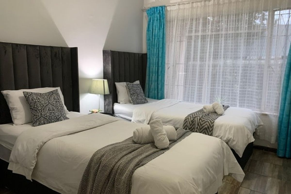 A well-maintained bedroom featuring tiled flooring and a large window with curtain tracks, providing ample natural light.