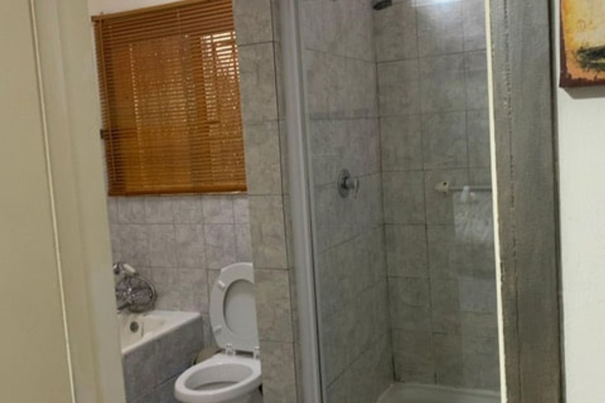 A functional bathroom featuring a separate shower enclosure, bathtub, and tiled finishes throughout.