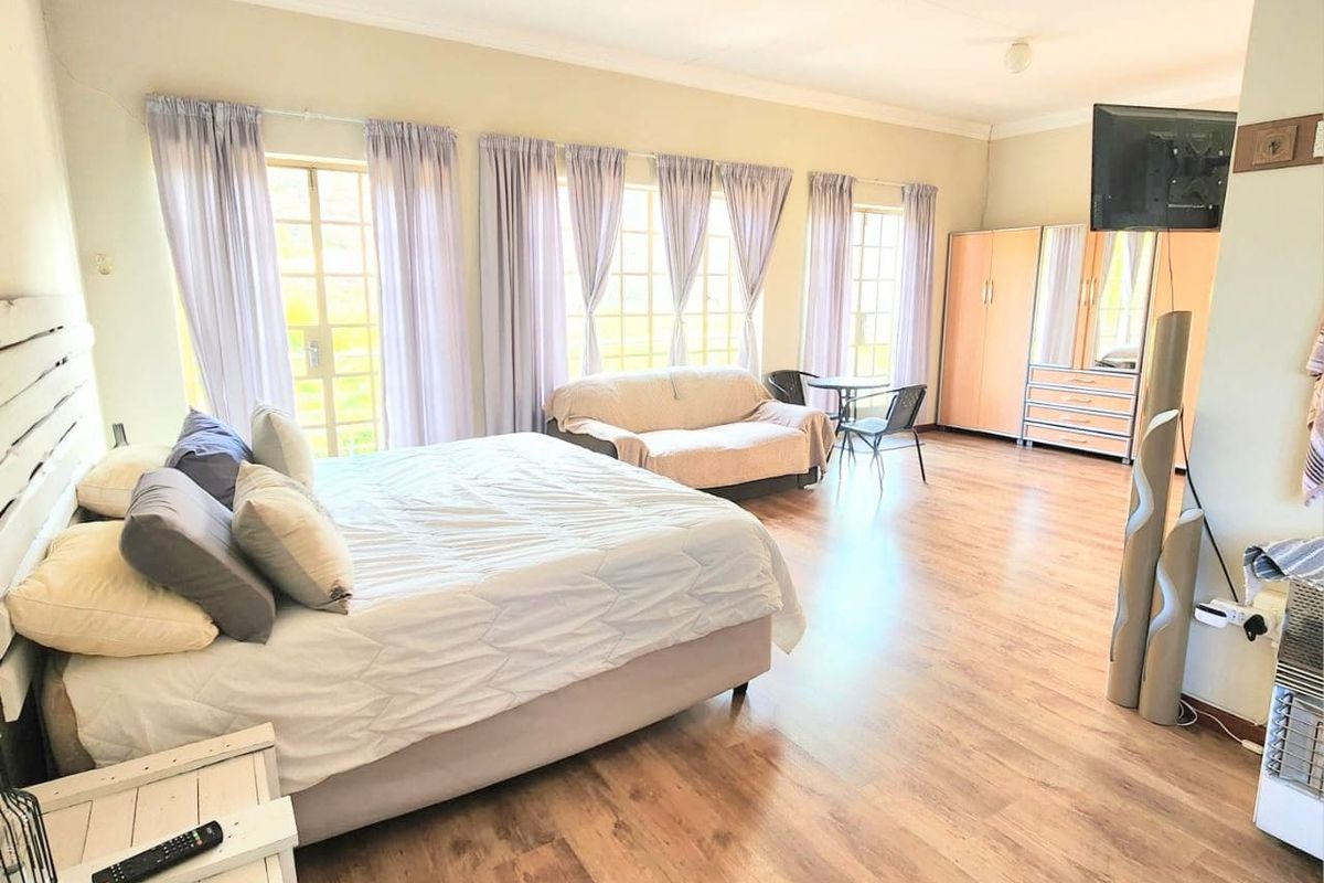 Spacious bedroom featuring laminate flooring, built-in cupboards, and multiple sets of french doors providing ample natural light.