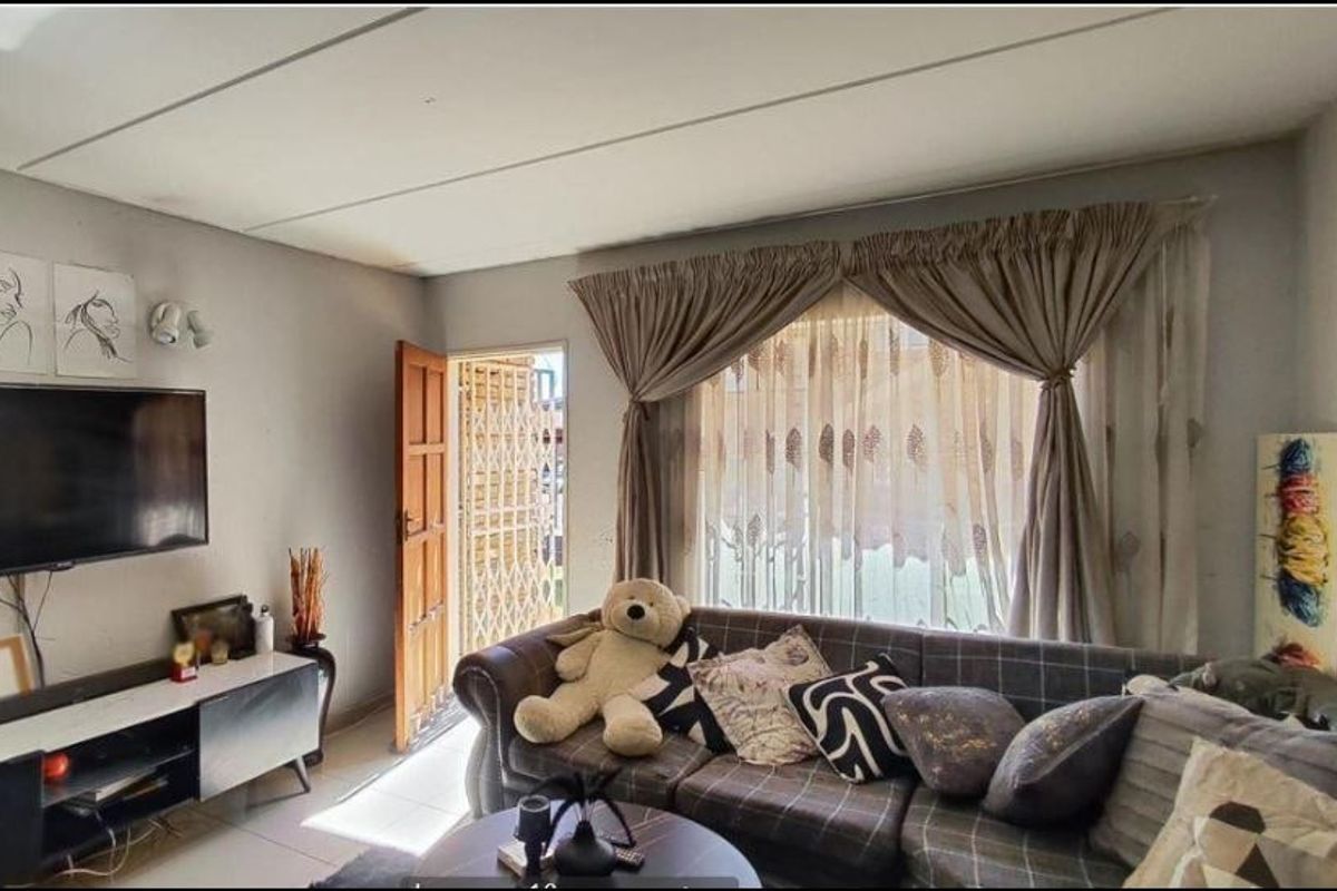 A living room featuring tiled flooring, a security gate at the entrance, and large windows with curtain tracks.