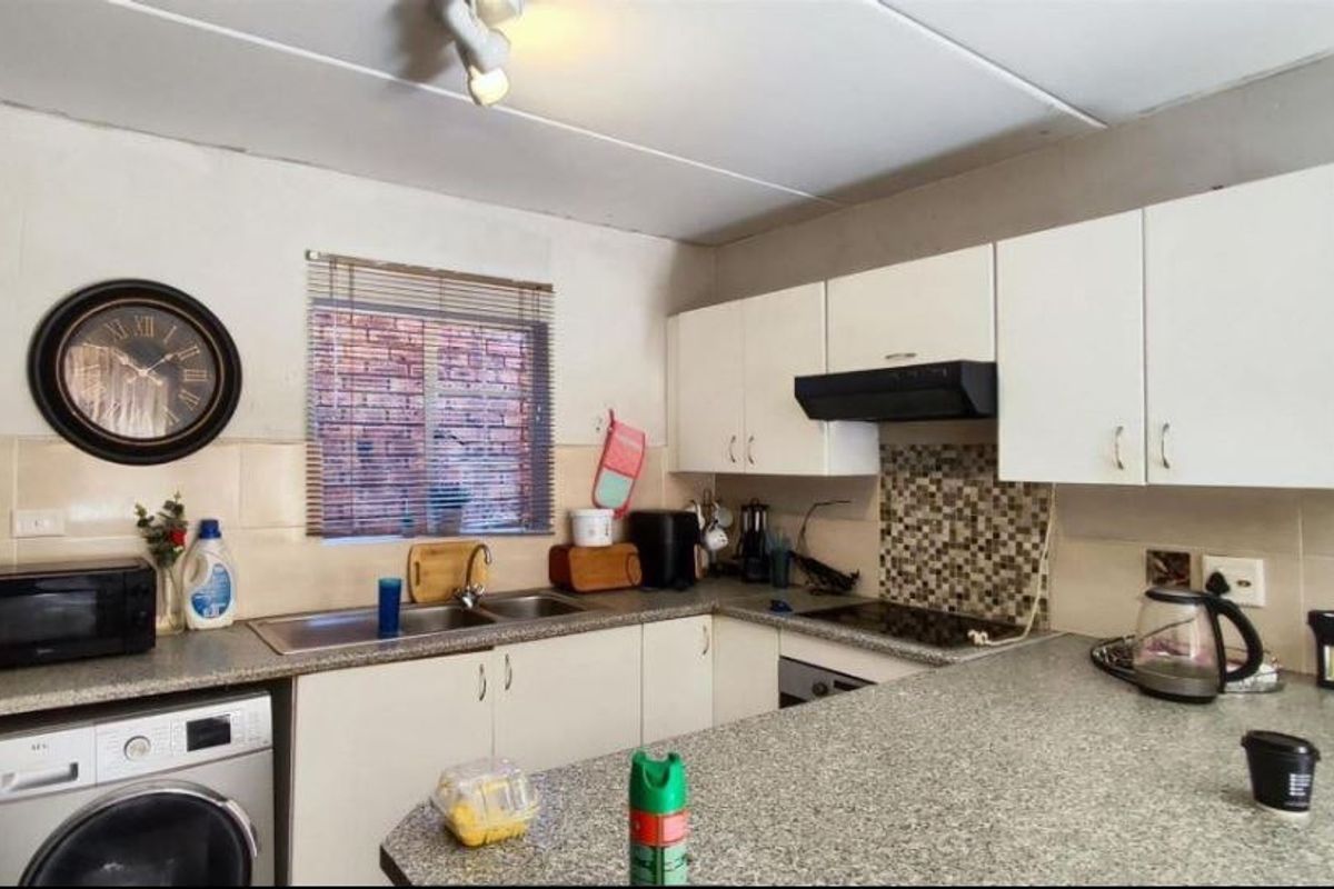 Functional kitchen featuring laminate countertops, mosaic tile backsplash, built-in cabinetry, and integrated appliances including an oven, hob, and washing machine.