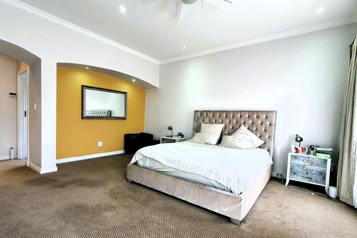 Spacious bedroom featuring neutral walls, a yellow accent wall with a recessed alcove, carpeted flooring, and integrated ceiling lighting.