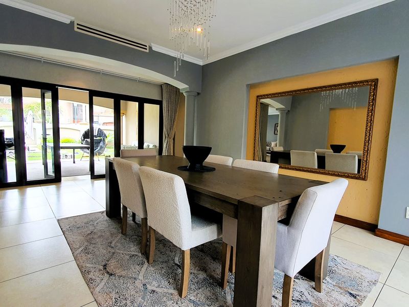 Spacious dining room featuring tiled flooring, decorative columns, and large sliding glass doors providing seamless access to the outdoor patio area.