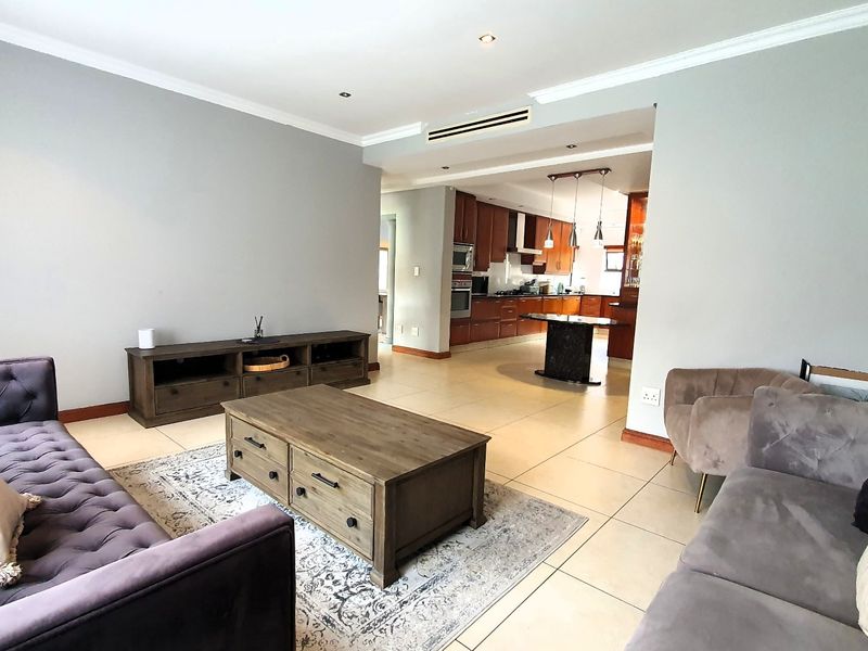 Spacious open-plan living area featuring tiled floors, recessed lighting, and a connected kitchen with built-in cabinetry and a central island.