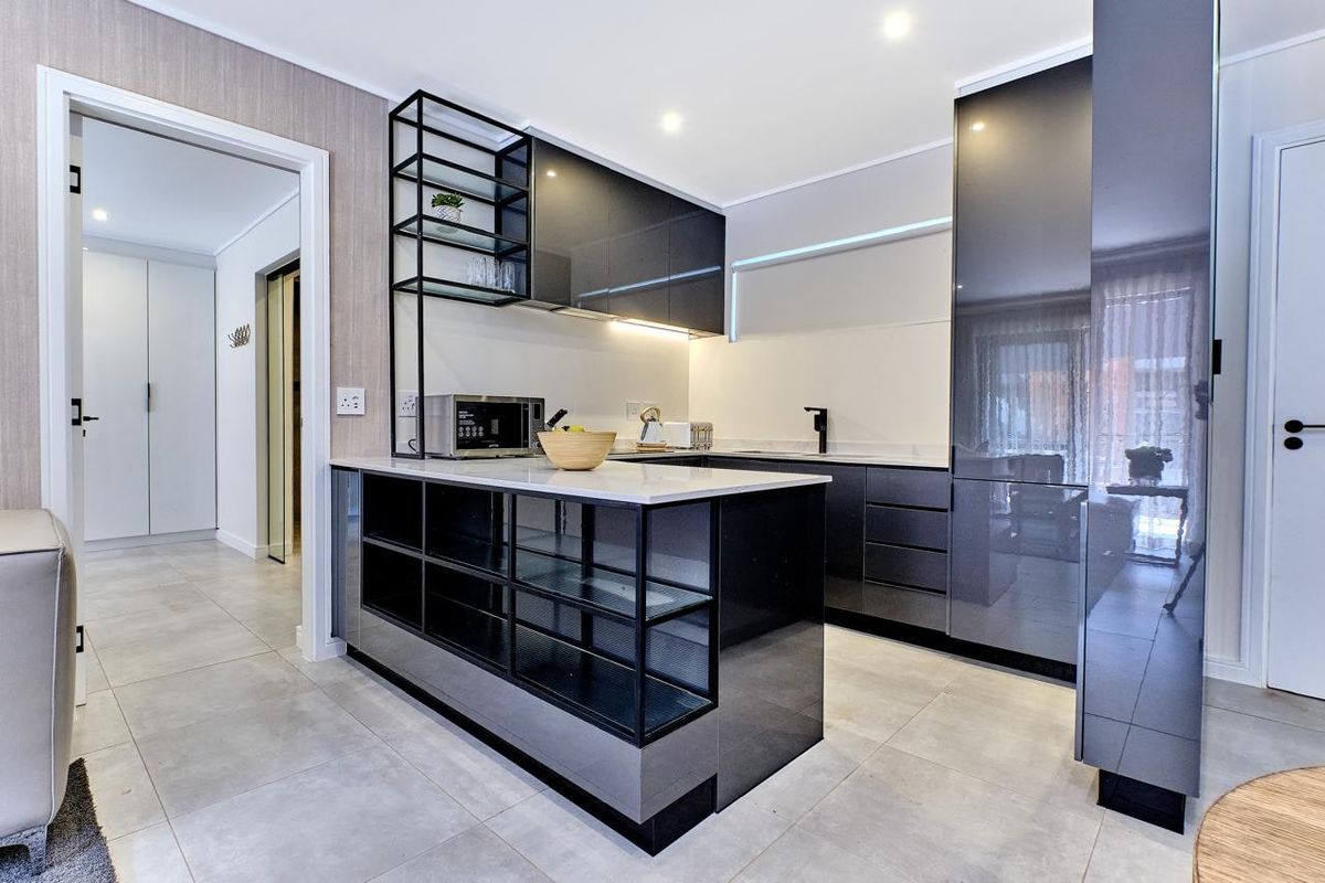 A modern, high-end kitchen featuring sleek dark cabinetry, stone countertops, integrated shelving, and premium finishes throughout.