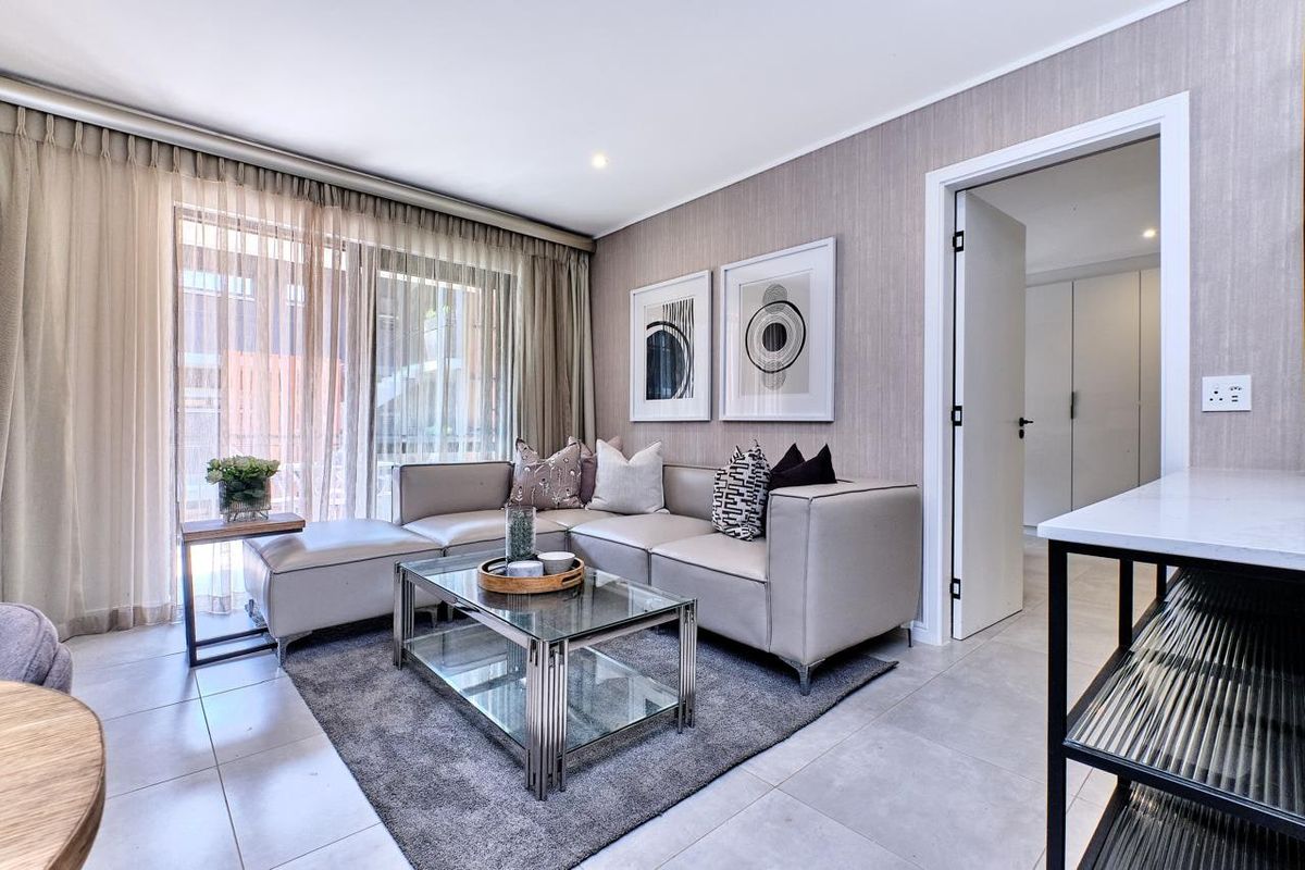A modern, well-maintained living room featuring neutral textured wallpaper, large sliding glass doors for natural light, and sleek tiled flooring.
