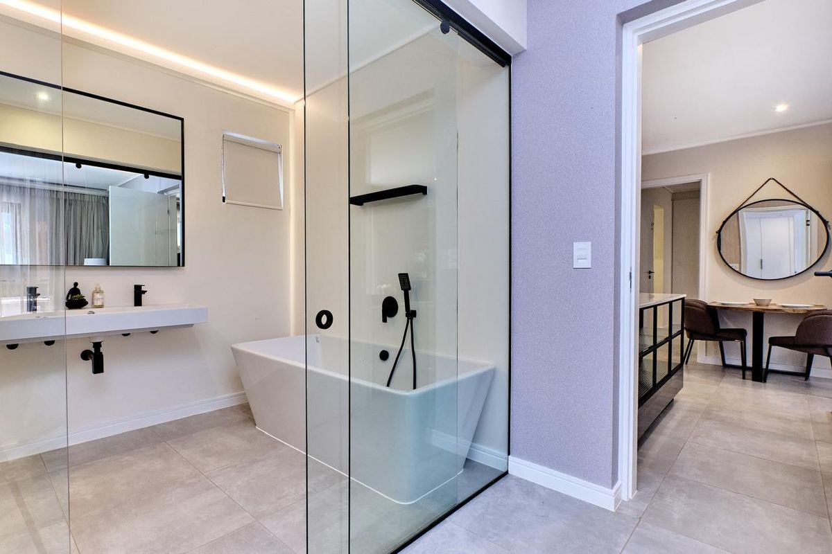 Modern bathroom featuring a sleek freestanding bathtub, glass-enclosed shower, wall-mounted basin, and contemporary black matte fixtures with high-quality tiled finishes.