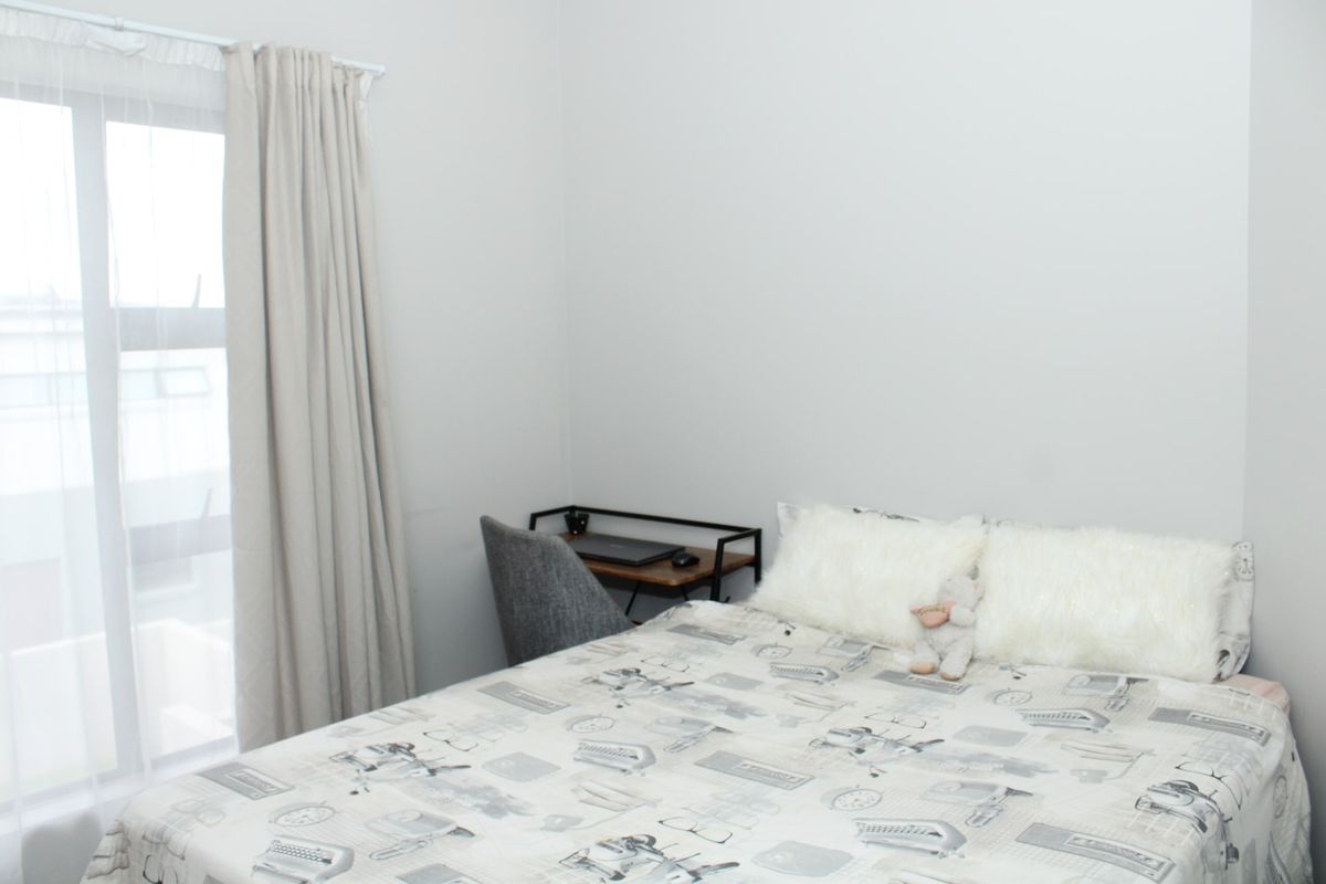 A bright and neutral bedroom featuring a large window that allows for ample natural light.