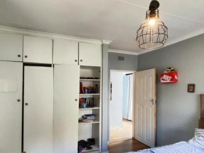 A bedroom featuring built-in floor-to-ceiling cupboards with integrated shelving and a classic panelled internal door.
