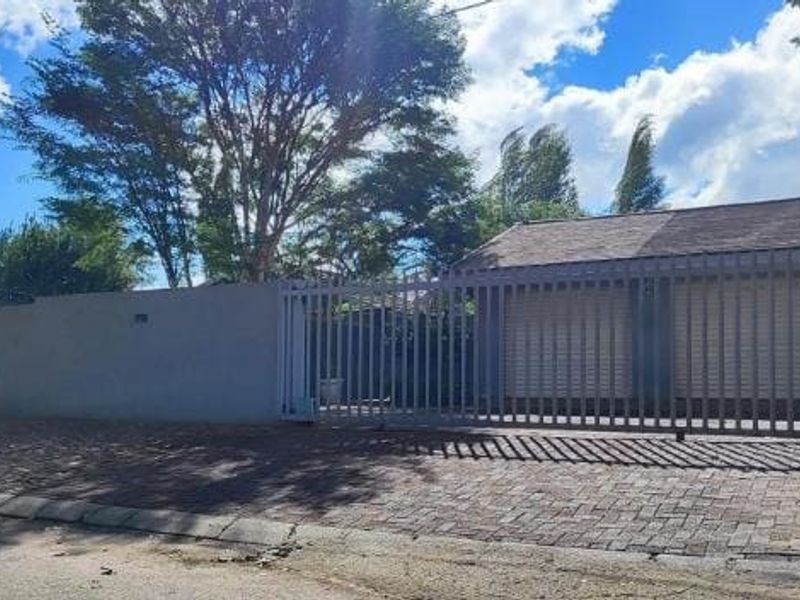 Front exterior view of the property featuring a paved driveway, secure perimeter wall, and a double garage with roller shutter doors.