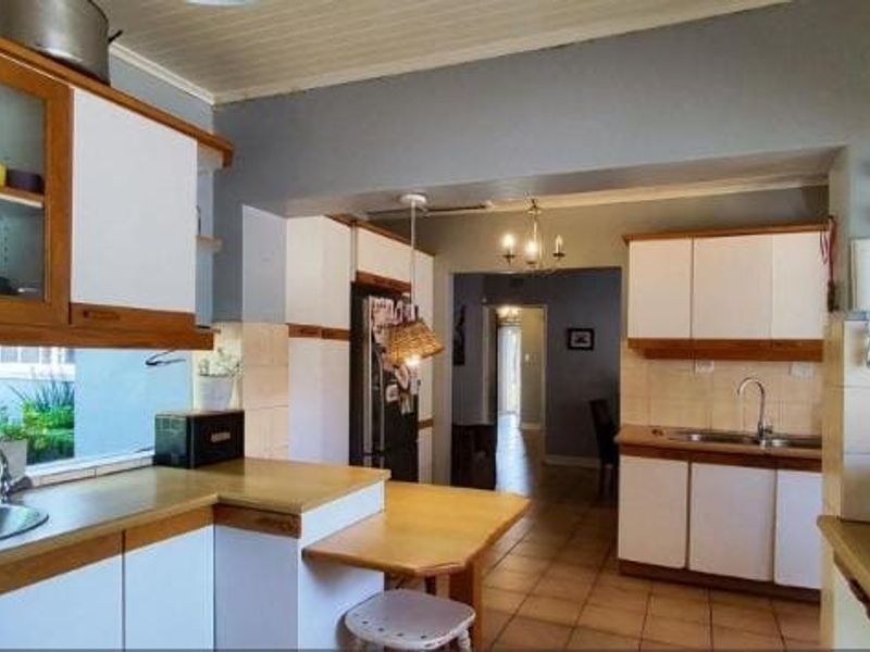 A functional kitchen featuring built-in cabinetry, laminate countertops, and a stainless steel sink, with a view through to the hallway.
