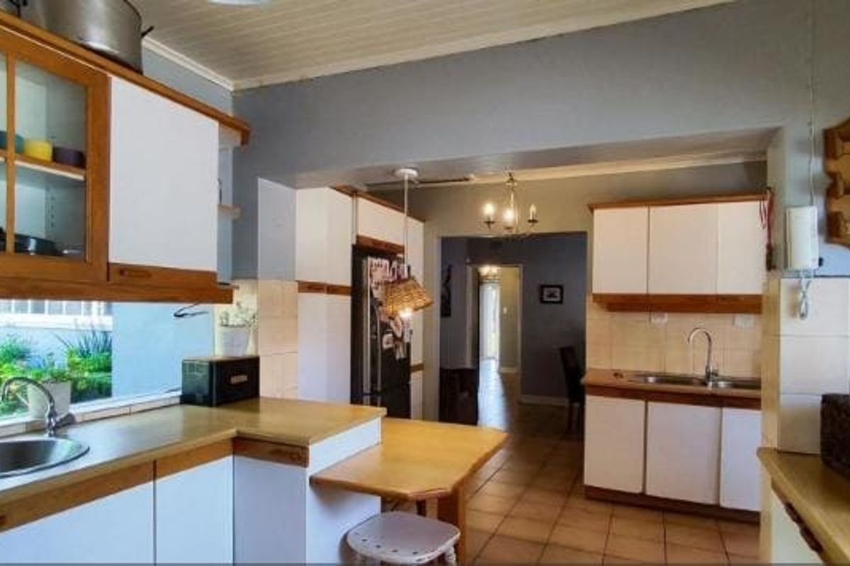 A functional kitchen featuring built-in cabinetry, laminate countertops, and a stainless steel sink, with a view through to the hallway.