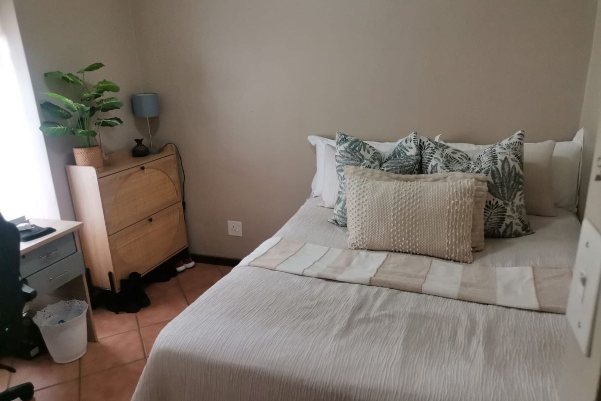 A cozy bedroom featuring terracotta floor tiles and neutral wall tones, providing a comfortable and functional sleeping space.