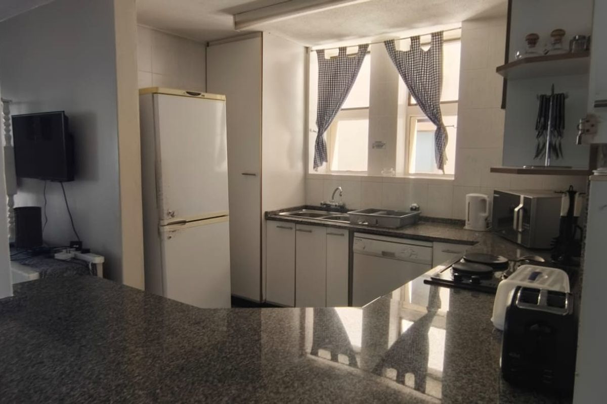 A functional kitchen featuring granite countertops, built-in cabinetry, a double sink, and a hob, offering a practical layout for daily meal preparation.