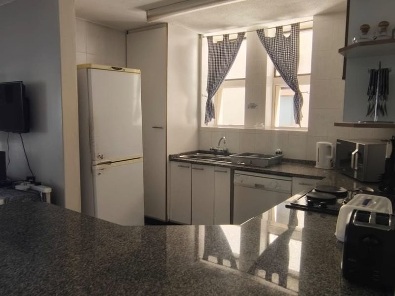A functional kitchen featuring granite countertops, built-in cabinetry, a double sink, and a hob, offering a practical layout for daily meal preparation.