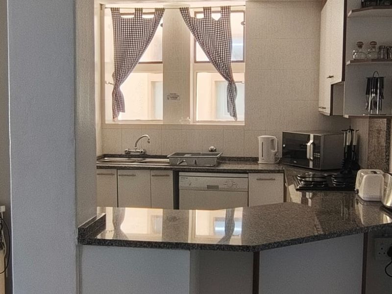Open plan kitchen featuring granite countertops, built-in cabinetry, and a gas hob, seamlessly connected to the living area.
