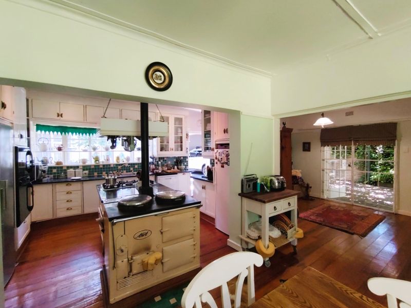 Open plan kitchen and living area featuring a classic Aga range cooker, hardwood flooring, and direct access to an outdoor patio through sliding glass doors.