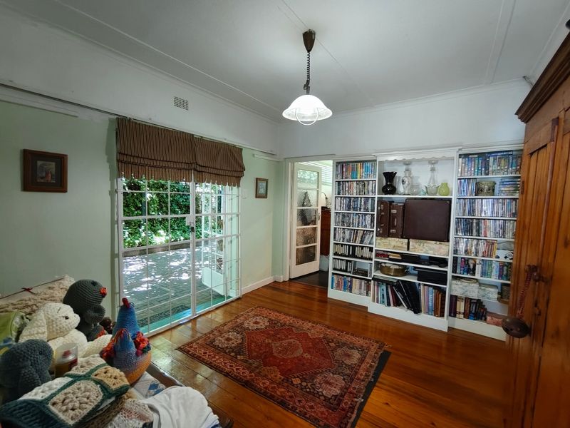 Living room featuring polished hardwood floors, built-in shelving units, and sliding glass doors providing direct access to the outdoor patio area.