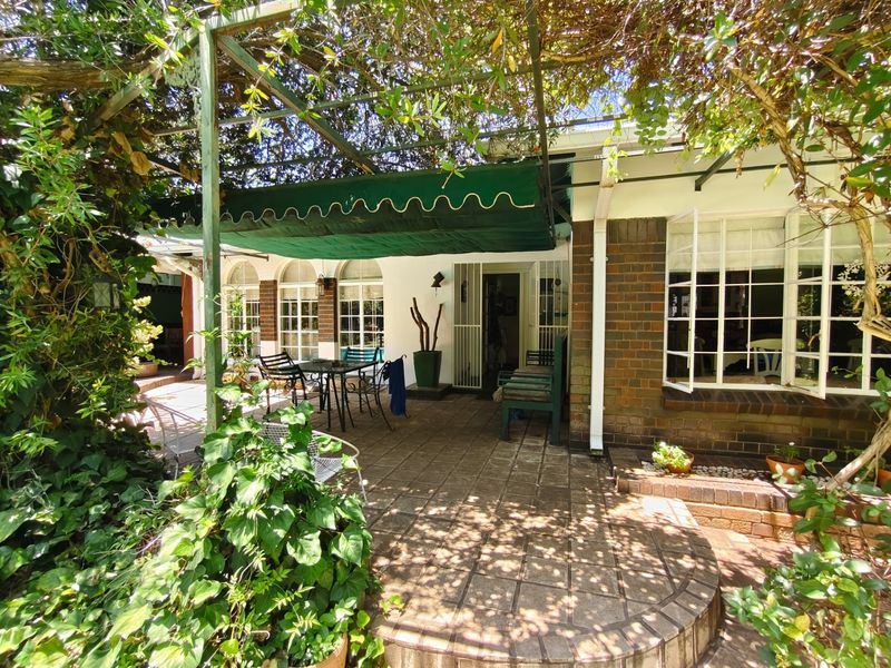 A covered outdoor patio area featuring paved flooring, a metal pergola structure with a retractable awning, and direct access to the home's interior.