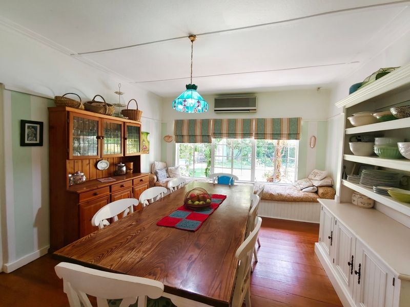 A dining room featuring timber flooring, a built-in window seat, and a split system air conditioner.