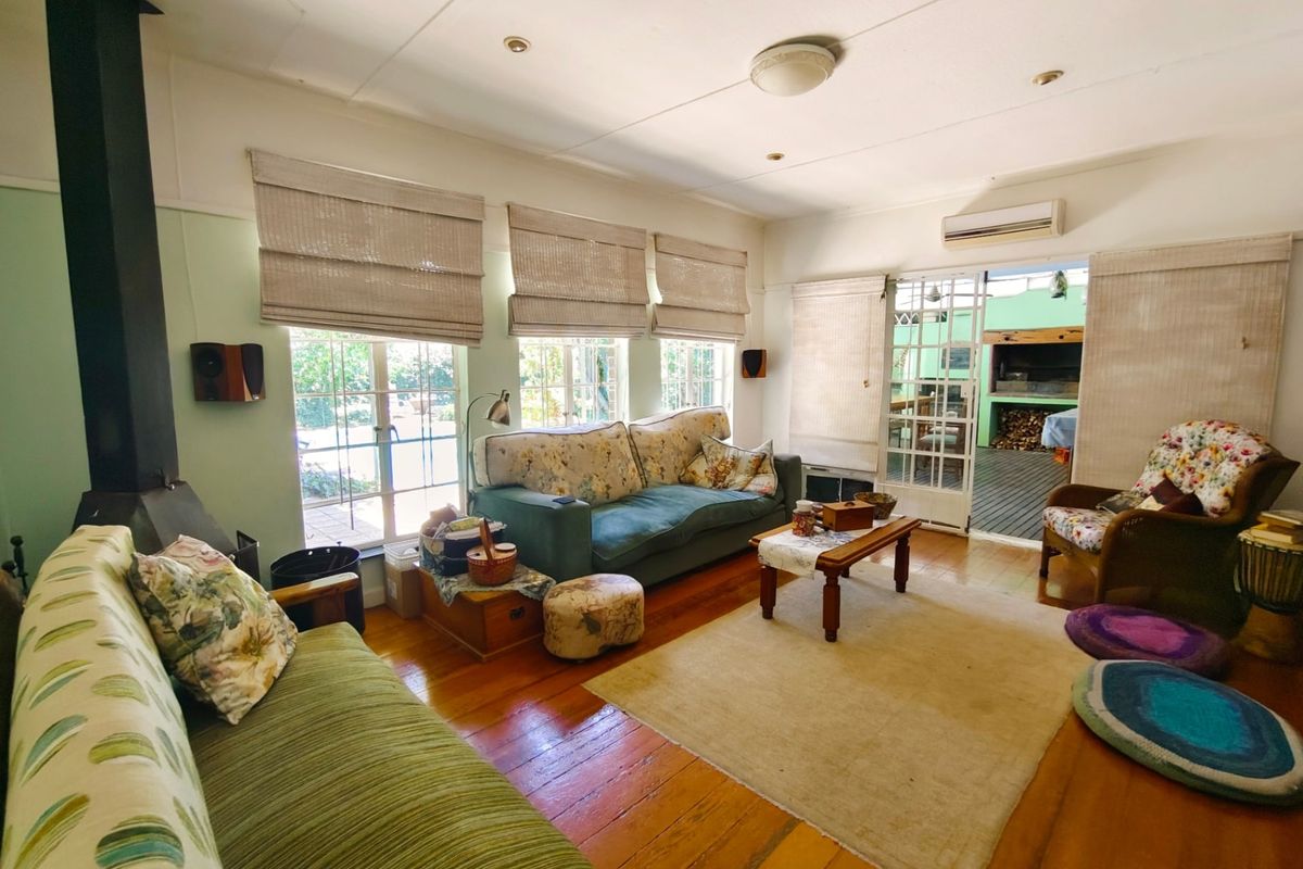 A cozy living room featuring polished hardwood floors, a freestanding fireplace, and direct access to an outdoor patio area through glass french doors.