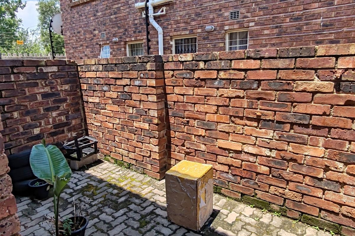A private rear courtyard featuring exposed brick boundary walls and paved flooring, offering a secure outdoor space for the apartment.