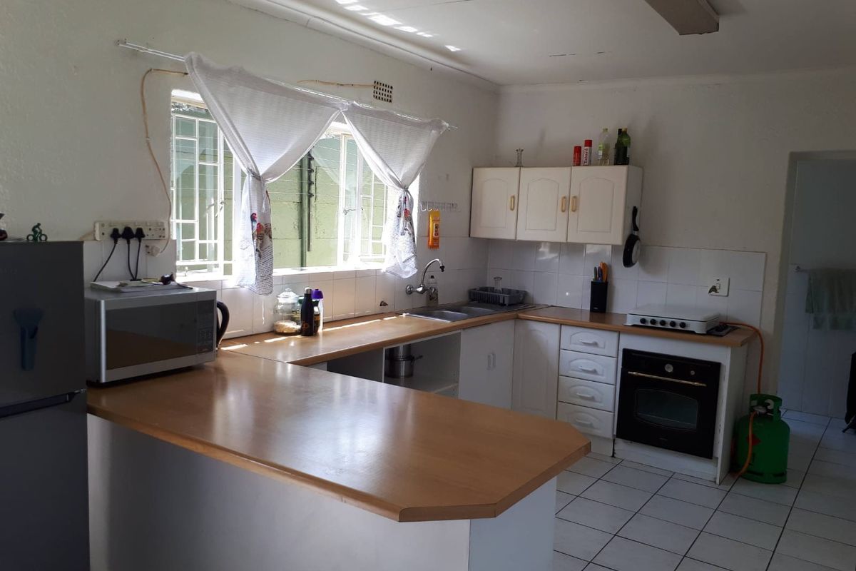 Functional kitchen featuring laminate countertops, built-in oven, gas hob, and tiled flooring, offering a practical layout with potential for modern cosmetic updates.