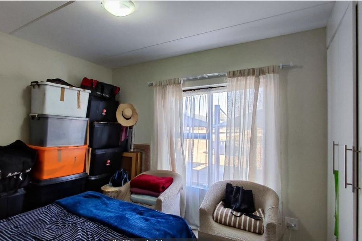 A bedroom featuring a built-in wardrobe and a window with curtain treatments, providing a functional space for rest.