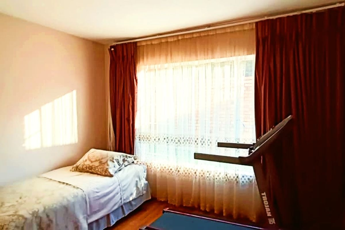 A bedroom featuring a large window with curtain rails, providing natural light and a view of the exterior.