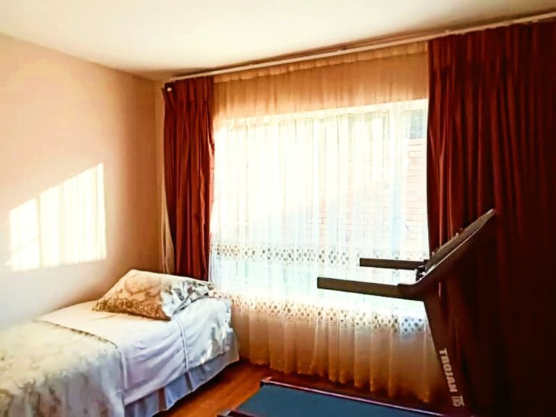 A bedroom featuring a large window with curtain rails, providing natural light and a view of the exterior.