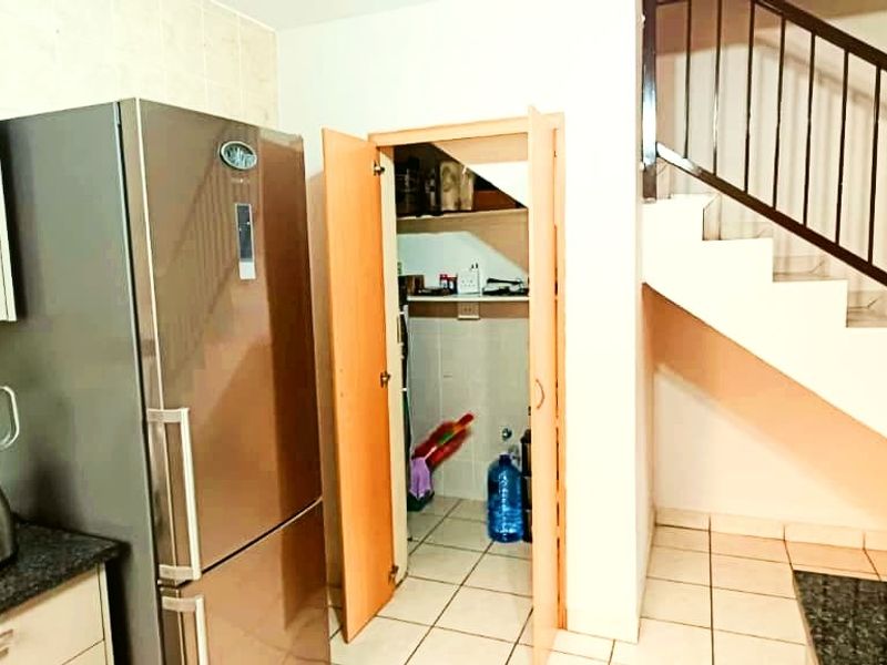 Kitchen area featuring granite countertops, built-in cabinetry, and an under-stair storage cupboard, with a staircase leading to the upper level.