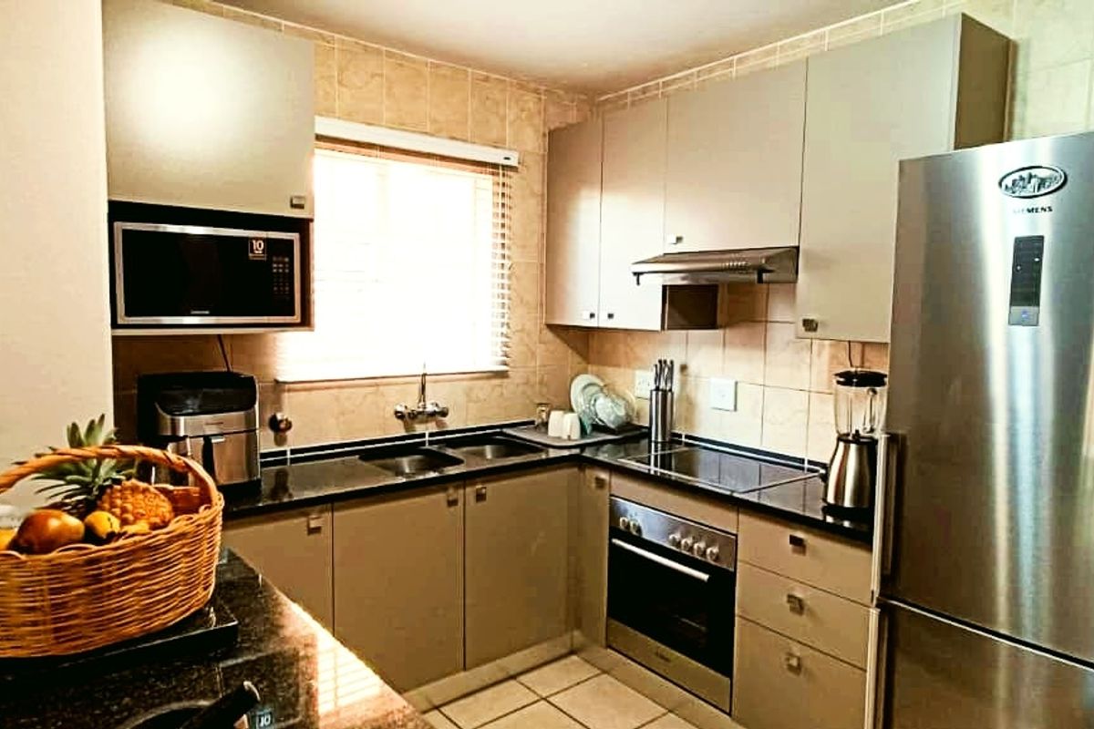 A functional kitchen featuring granite countertops, built-in cabinetry, integrated oven and hob, and a tiled backsplash, providing a practical and well-organized cooking space.