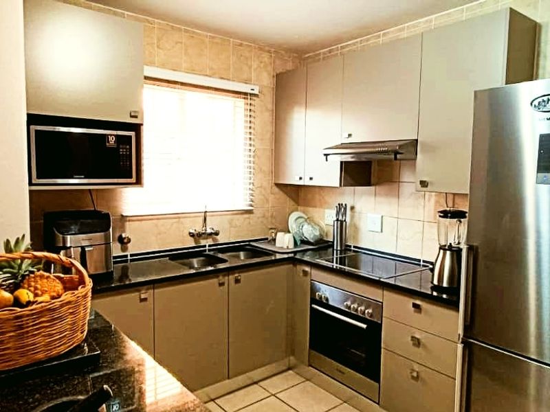 A functional kitchen featuring granite countertops, built-in cabinetry, integrated oven and hob, and a tiled backsplash, providing a practical and well-organized cooking space.