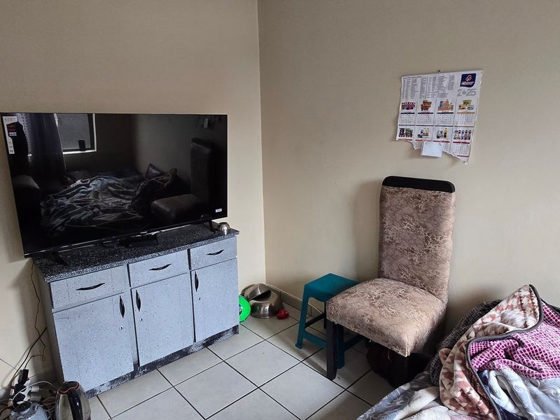 A compact living area featuring tiled flooring and neutral wall finishes, providing a functional space for daily use.