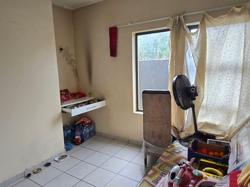 A bedroom featuring tiled flooring and a wall-mounted shelf, currently showing signs of wear and requiring cosmetic updates to improve its overall condition.