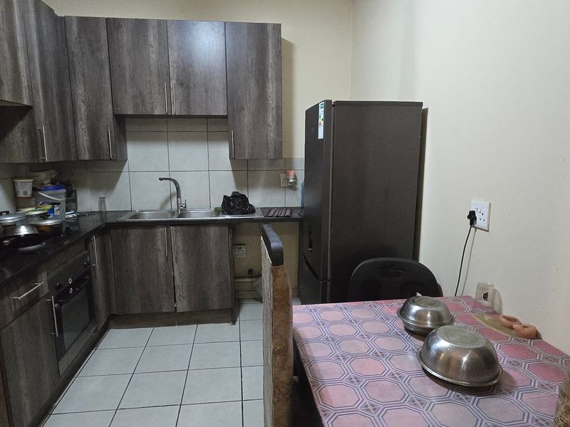 A functional kitchen featuring dark wood-look cabinetry, laminate countertops, a built-in oven, and tiled flooring, providing a practical workspace for daily cooking.