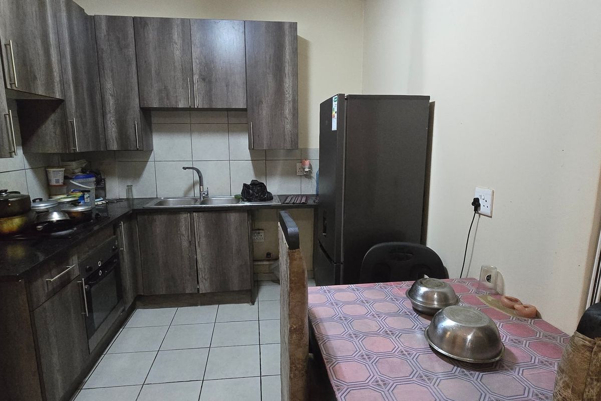 A functional kitchen featuring dark wood-look cabinetry, laminate countertops, a built-in oven, and tiled flooring, providing a practical workspace for daily cooking.