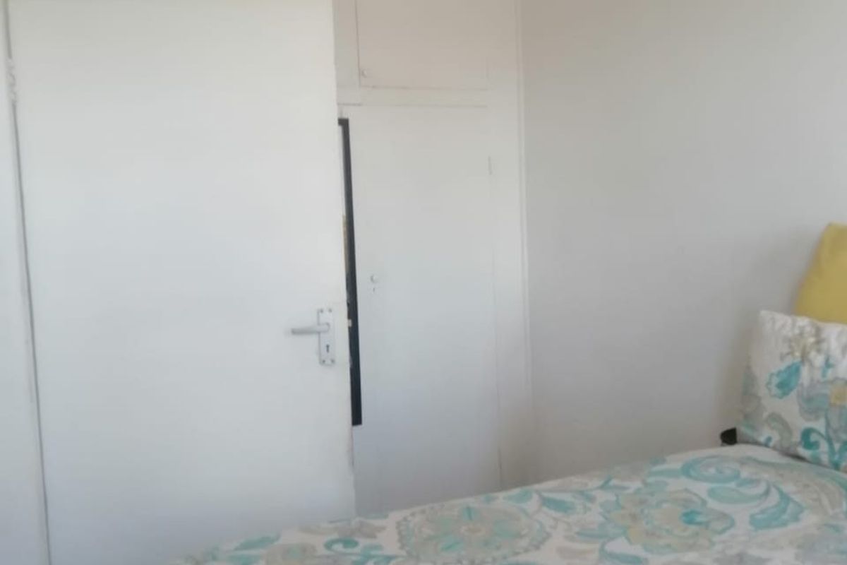 A bedroom featuring a built-in cupboard with overhead storage, providing functional storage space within the room.