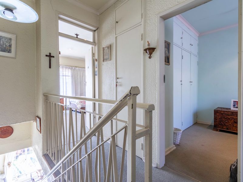 A residential hallway featuring a metal balustrade, built-in storage cupboards, and access to adjacent rooms.