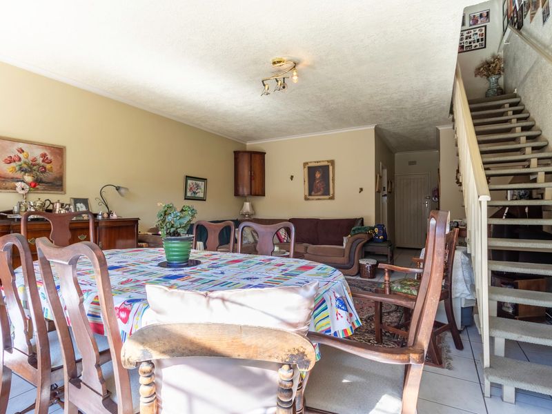 Open plan living and dining area featuring tiled flooring and a staircase leading to the upper level.
