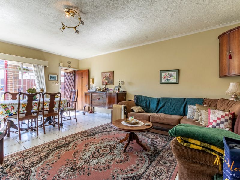 Open plan living and dining area featuring tiled flooring, textured ceilings, and direct access to the exterior through a sliding glass door.