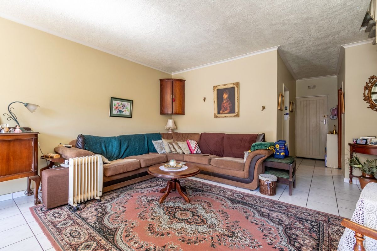 A living room featuring tiled flooring, a textured ceiling, and a built-in corner wall cabinet, offering a functional and traditional layout.