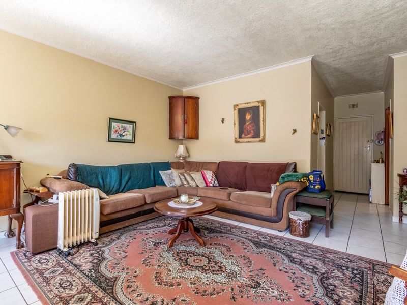 A living room featuring tiled flooring, a textured ceiling, and a built-in corner wall cabinet, offering a functional and traditional layout.