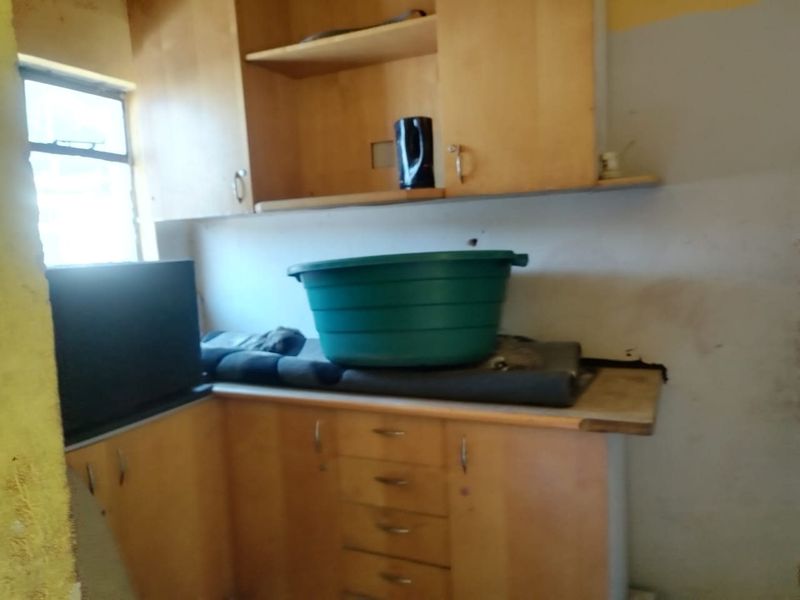 A dated kitchen area featuring wooden cabinetry and laminate countertops, currently in need of significant renovation and cosmetic updates.