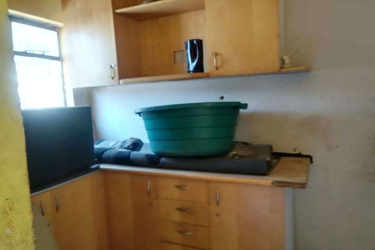 A dated kitchen area featuring wooden cabinetry and laminate countertops, currently in need of significant renovation and cosmetic updates.