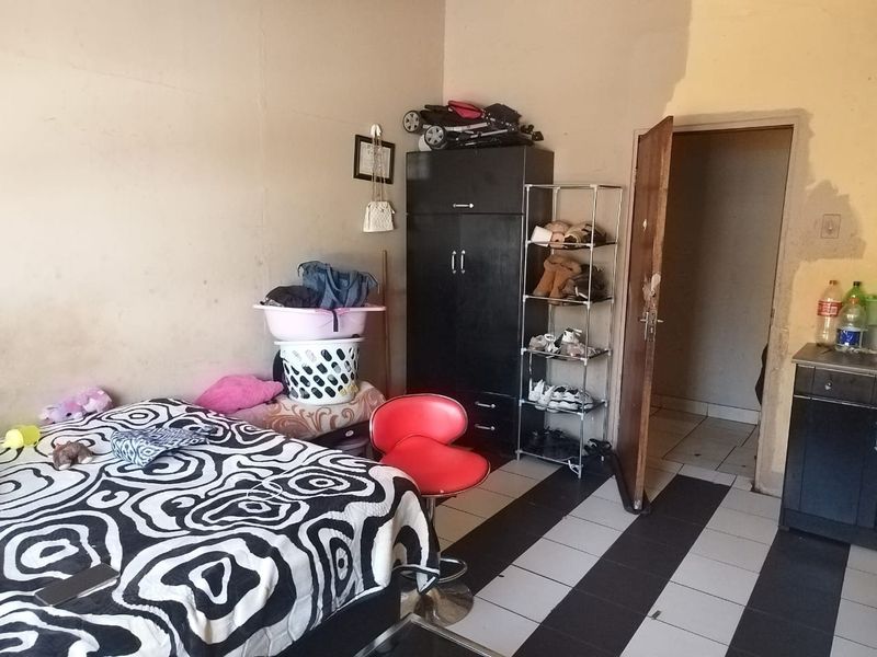 A bedroom featuring tiled flooring and an internal door, currently requiring wall repairs and fresh paint to improve the overall condition.
