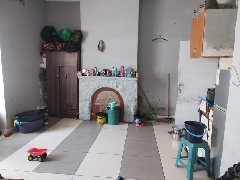 Living room featuring a stone fireplace and tiled flooring, requiring cosmetic updates and wall repairs to improve the overall condition.