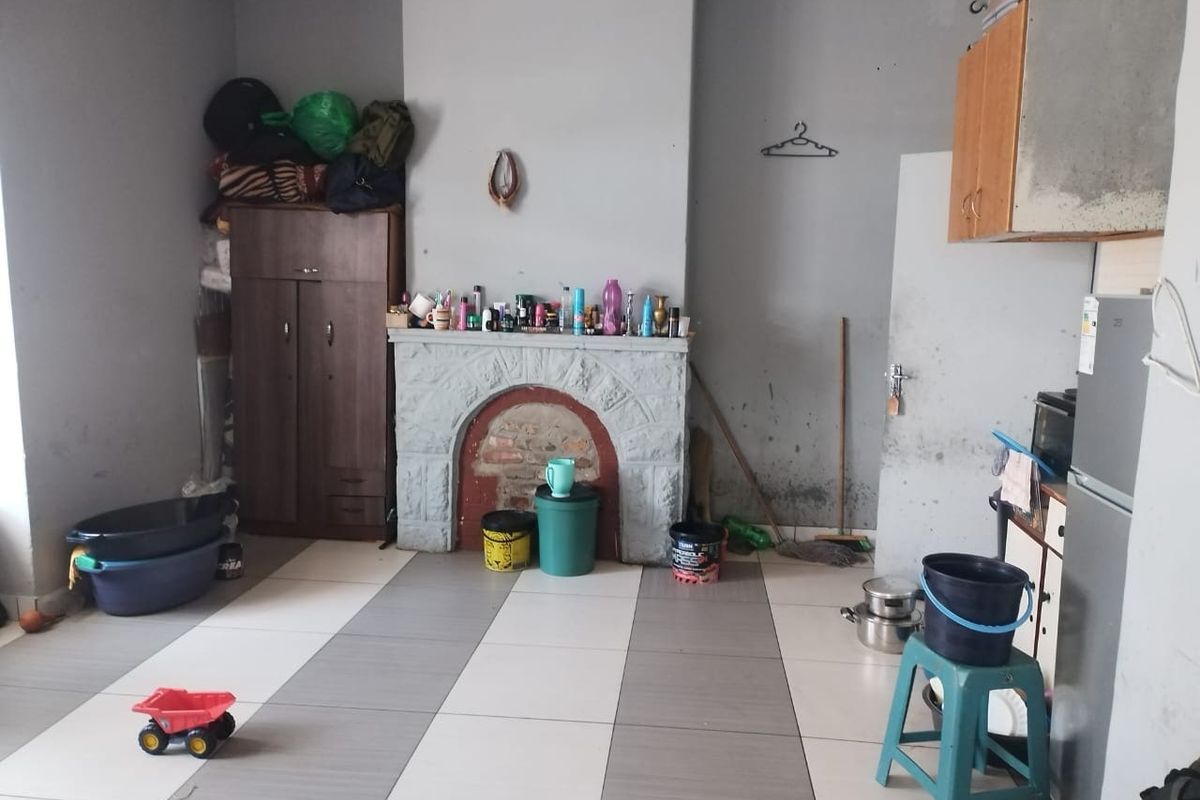 Living room featuring a stone fireplace and tiled flooring, requiring cosmetic updates and wall repairs to improve the overall condition.